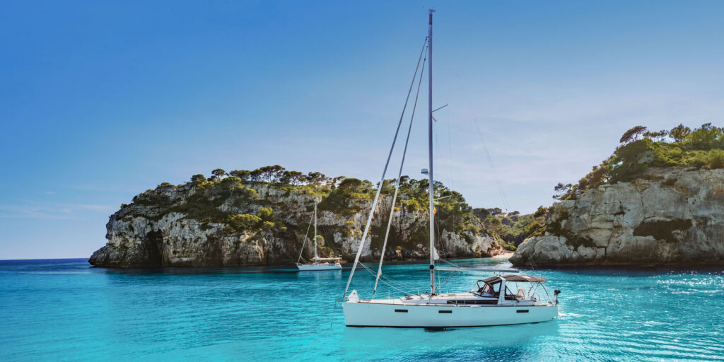 Beautiful beach with sailing boat yacht to answer the following question: To avoid crowds, when should I plan a trip to Mallorca?